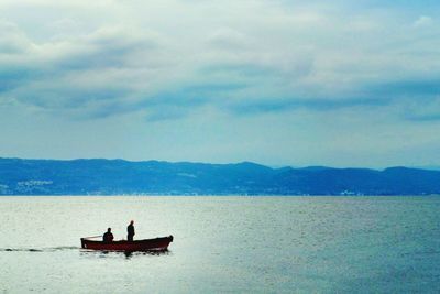 Man in boat on lake against sky