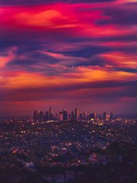 Aerial view of illuminated cityscape against sky during sunset