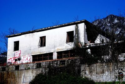 Low angle view of abandoned building against clear blue sky