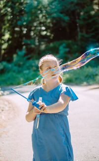 Rear view of young woman blowing bubbles in park