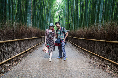 Young couple standing on walkway amidst bamboos at park