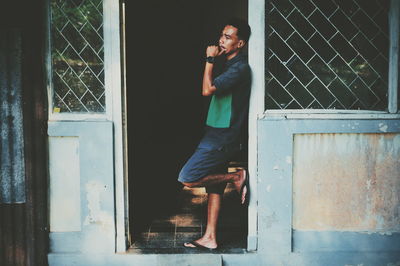 Side view of young man looking through window