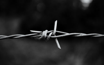 Close-up of barbed wire on fence against blurred background