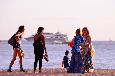 People walking on beach by sea against sky