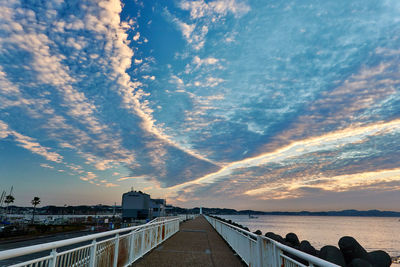 Bridge over sea against sky during sunset