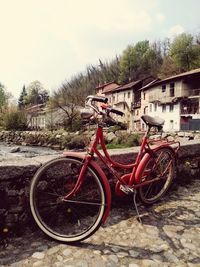 Bicycle parked by abandoned building against sky