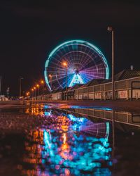 Illuminated ferris wheel in city at night