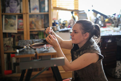 Craftsman woman works with decoration, makes the base of copper metal under the enamel, the concept 