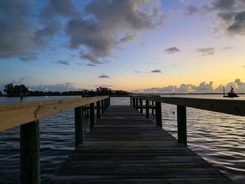 Wooden pier over sea against sky during sunset