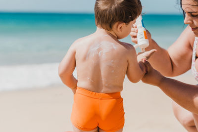 Rear view of shirtless man standing at beach