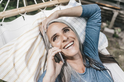 Portrait of laughing woman on the phone lying in hammock