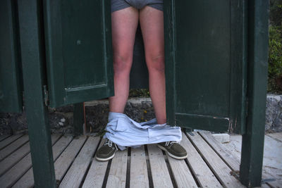 Low section of man with pants down standing on wooden floor