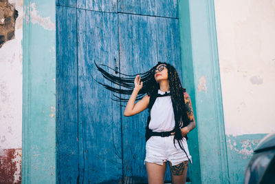 Woman tossing hair while standing against wall