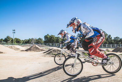 Side view of people riding bicycled on sunny day