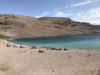 People on beach by mountain against sky