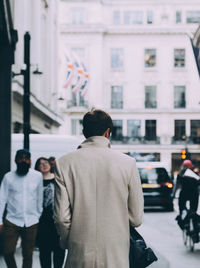 Rear view of people walking on street in city