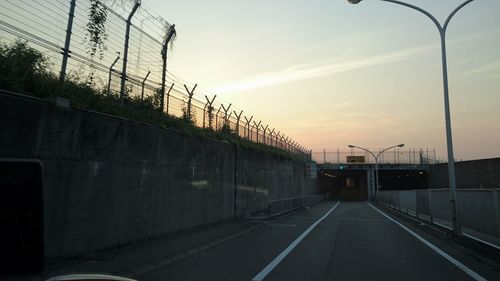 Road by bridge against sky during sunset