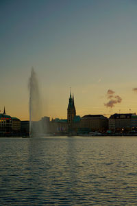 View of hamburg buildings at waterfront during sunset