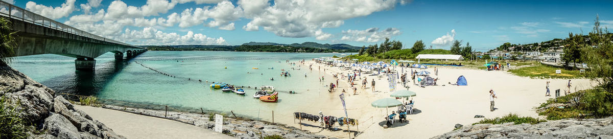 Panoramic view of people on beach against sky