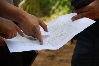 Midsection of people holding map