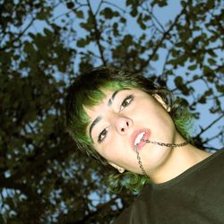 Portrait of smiling young woman against tree