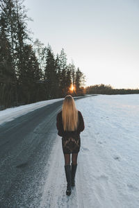 Rear view of woman walking on snow covered road