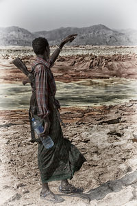 Rear view of person standing on rock at beach