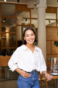 Portrait of smiling young woman standing at home