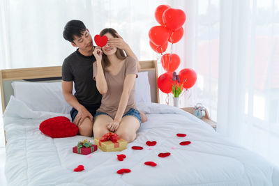 Rear view of couple walking on red balloons