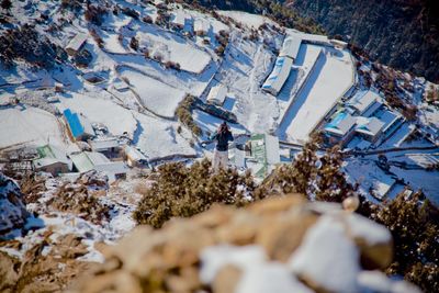 High angle view of person standing in mountain over snowy field during sunny day