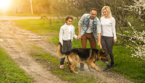 Side view of couple with dog on field