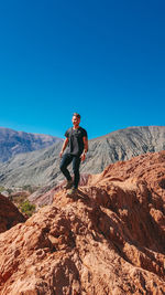 Full length of man on rock against clear blue sky