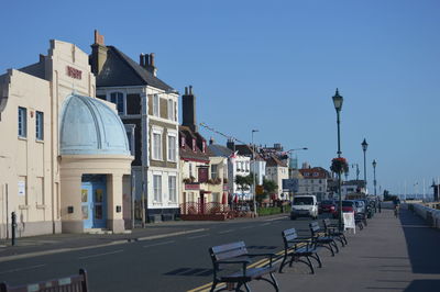 Street amidst buildings against clear blue sky