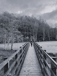 Black and white woman walking across a wooden bridge