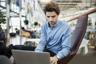 Businessman using laptop at airport lobby