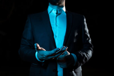 Midsection of businessman standing against black background