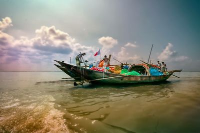 Boats in sea against cloudy sky