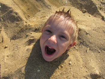 High angle portrait of playful boy in sand