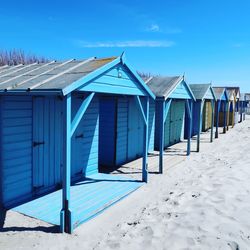 Blue beach huts in row during sunny day