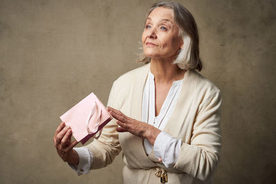Midsection of woman holding paper while standing against wall