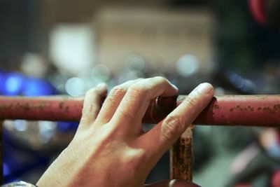 Close-up of hand holding rusty metallic railing