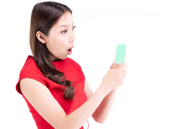 Young woman looking away while standing against white background
