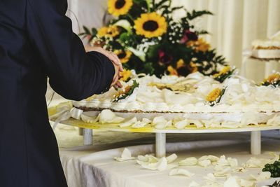Midsection of man standing by flowers