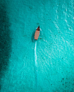 A high angle view of a boat sailing through the aqua blue ocean water