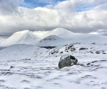 Scenic view of snowcapped mountains against cloudy sky