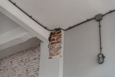 Low angle view of damaged white brick wall