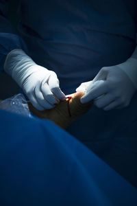 Midsection of doctor doing surgery of patient in operating room