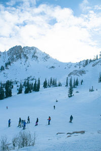 Group of snow skiers on snowcapped mountain against sky