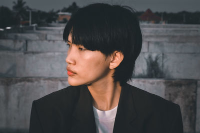 Portrait of young woman standing against wall