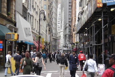 People walking on road amidst buildings in city